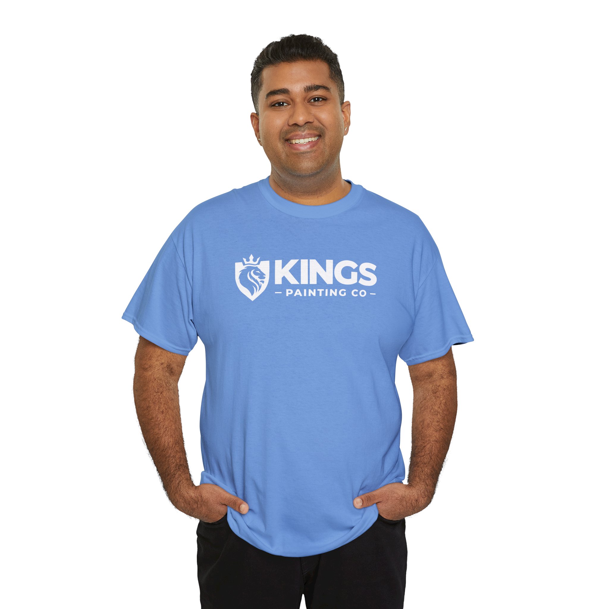A smiling man stands with his hands in his pockets against a white background, wearing the Kings Painting Co. Logo T‑Shirt (Classic) made from Gildan Ultra Cotton (G5000), featuring the KINGS PAINTING CO logo and emblem on the front in light blue.