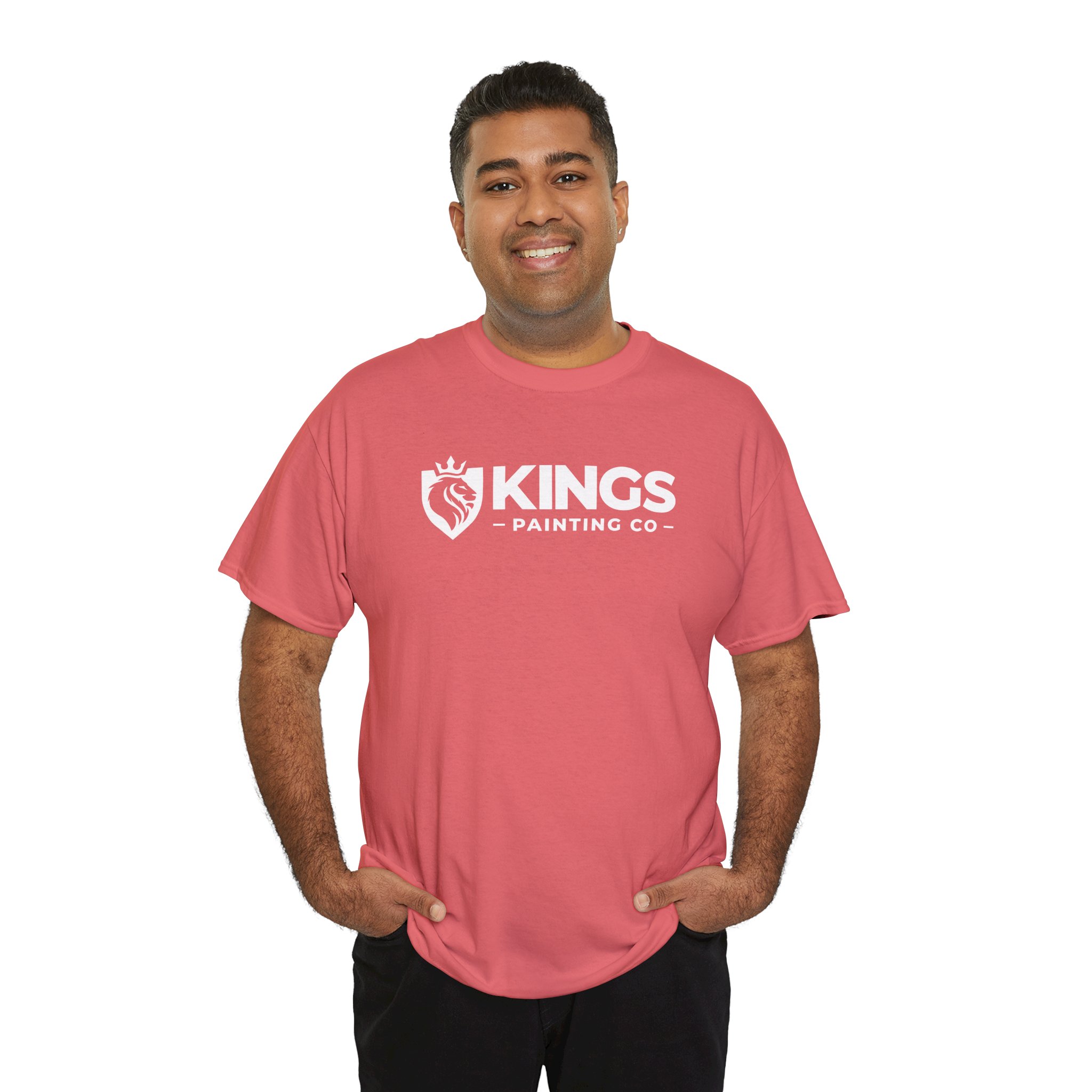 A smiling person stands with hands in pockets, wearing the Kings Painting Co. Logo T‑Shirt (Classic) | Gildan Ultra Cotton (G5000) in pink with a white logo, set against a plain white background.